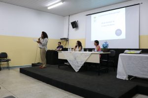 Na imagem, a articuladora Perla Assunção, fala no palco sobre leitura inclusiva